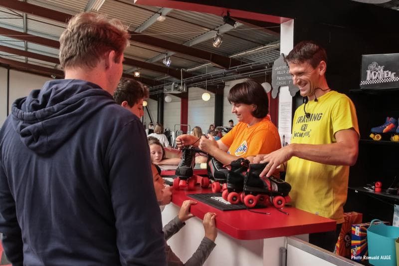 Le comptoir de location : l’équipe remet une paire de rollers à un visiteur